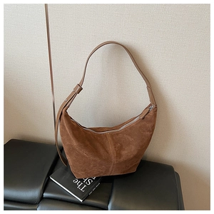 Gros plan sur la texture du cuir mat et la fermeture éclair premium du sac porté épaule marron