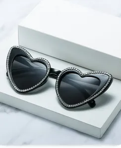 Détail macro de lunettes de soleil en cœur avec strass brillants sur des blocs blancs