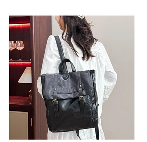 Retro black PU leather satchel backpack with buckle straps shown on model in indoor setting