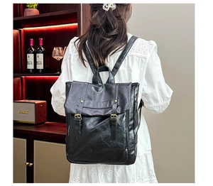Retro black leather backpack detail with vertical buckle straps and a side zipper pocket
