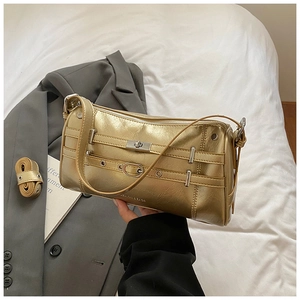 Detailansicht goldene Schultertasche mit Silberschnallen und Nieten auf Stoffhintergrund