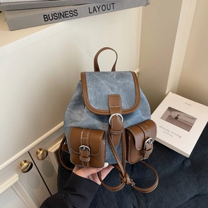 Vintage denim backpack with brown leather trim and white stitching for outdoor travel