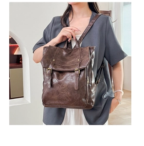 Close-up of vintage dark brown distressed leather backpack with buckle straps and fine texture
