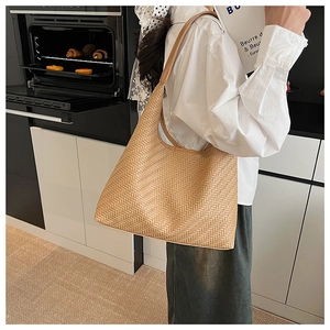Detail of caramel woven tote bag showing herringbone texture and wide shoulder strap