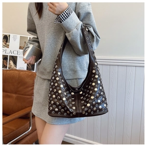 Détail du sac bandoulière en cuir marron foncé avec rivets argentés et œillets en métal