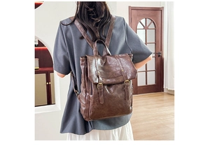 Brown vintage style backpack shown worn by a model in a warm indoor lifestyle setting