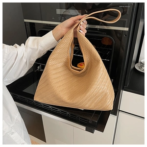 Detail of camel brown leather woven tote bag showing the textured braided pattern craftsmanship