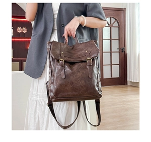 Detail of vintage brown leather backpack showing dual buckle straps and top handle grip