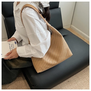 Detailed view of woven beige hobo bag with intricate leather texture and wide strap