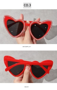 Vue détaillée des lunettes de soleil en forme de cœur rouge vif avec strass brillants