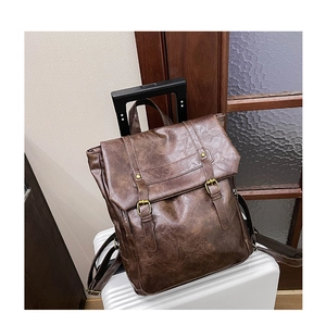 Close-up of vintage brown leather backpack with gold buckles on a white suitcase handle