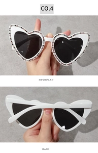 Vue détaillée de lunettes de soleil en forme de cœur avec monture blanche et strass colorés