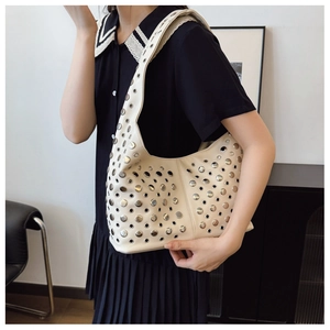 Détail du sac Hobo blanc cassé avec rivets argentés porté à l'épaule par un mannequin