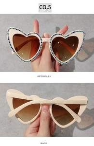 Détail de lunettes de soleil en forme de cœur avec strass colorés et verres dégradés