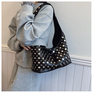 Détail d'un sac seau punk avec clous argentés et œillets métalliques sur cuir noir