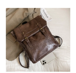 Detailed view of dark brown vintage leather backpack with metal buckles and fine grain texture