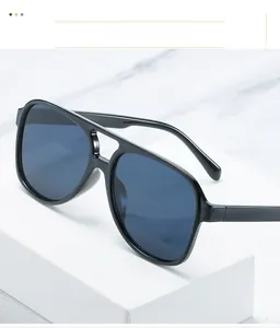 Close-up of black double-bridge aviator sunglasses with dark blue lenses on marble