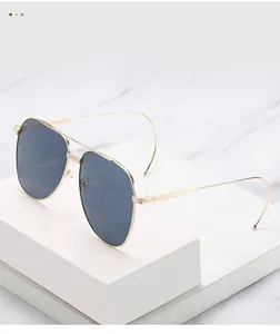 Détail de lunettes de soleil aviateur dorées avec verres foncés sur marbre