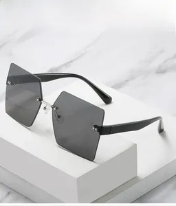 Close-up of rimless square sunglasses with dark grey lenses and wide black temples on marble