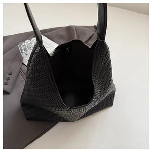 Close-up of black woven leather tote bag showing magnetic closure and intricate texture