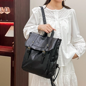 Vintage black leather backpack with dual buckle straps and top handle in a lifestyle setting