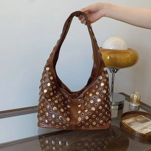 Sac hobo marron avec clous et oeillets argentés présenté dans un cadre de style de vie