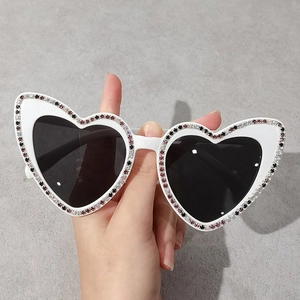 Lunettes de soleil chic en forme de cœur blanc avec strass colorés et verres foncés en main