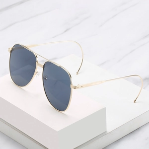 Lunettes aviateur dorées classiques avec verres foncés et branches courbées sur marbre