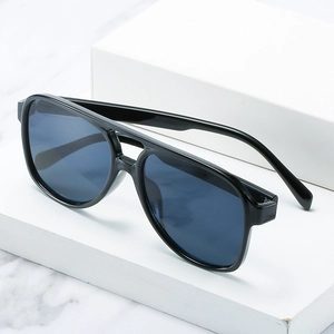 Classic black pilot sunglasses with deep blue lenses on a white marble background