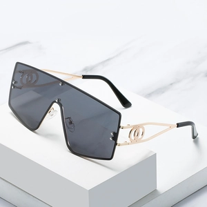 Oversized flat top shield sunglasses with gold metal hollow temples on marble stand