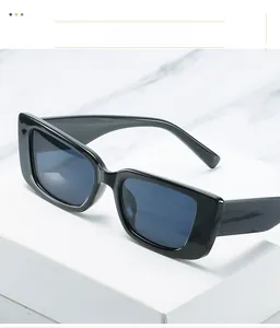 Close-up of black square frame sunglasses on a white stand with marble background