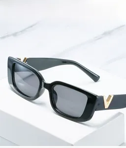 Detail of black square sunglasses featuring a signature gold V-shaped metal logo on the temple