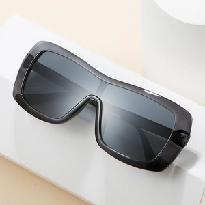 Modern oversized one-piece sunglasses with transparent dark grey frame on white props