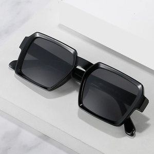 Retro rectangle sunglasses with matte black frames and dark grey lenses on stone surface
