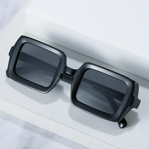 Fashionable black square sunglasses with thick frames on minimal marble background