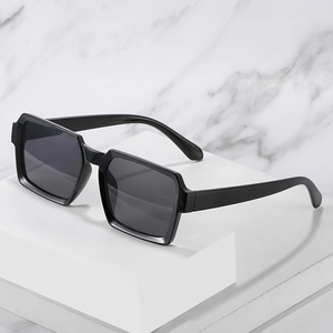 Classic black rectangular sunglasses with dark lenses on a minimalist stone display