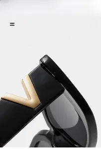 Macro shot of black square sunglasses featuring a signature gold metal V-detail on the temple