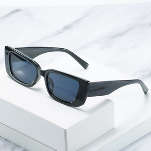 Retro square sunglasses with glossy black frames and dark blue lenses on a marble surface
