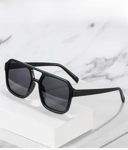 Close-up of black square double-bridge sunglasses on a white geometric marble pedestal