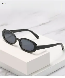 Détail de lunettes de soleil ovales noires avec verres gris sur fond de marbre