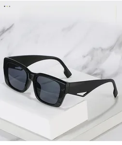 Detail view of black rectangular sunglasses with hollow triangle temples on marble