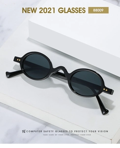 Close-up of retro black round frame sunglasses with gold rivet details on white marble