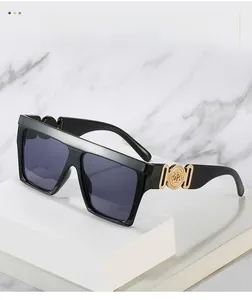 Detail of black oversized sunglasses featuring golden relief emblem and hollow temple design