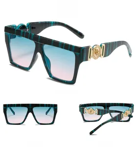 Macro detail of square striped marble sunglasses with gold floral relief and gradient lenses