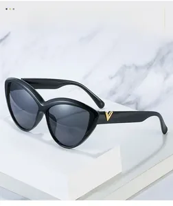 Detailed view of large cat-eye sunglasses with gold metal V logo on temple arm
