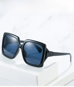 Détail de lunettes de soleil carrées avec monture noire et verres bleu foncé