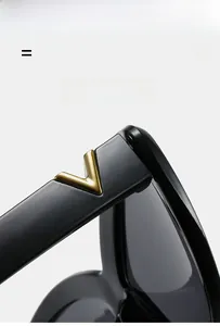 Macro shot of black acetate eyewear temple with an inlaid gold metal V-shaped logo detail