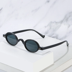 Retro hip hop round sunglasses with black frames and gold rivet details on white marble