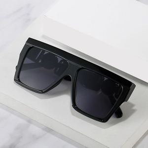 Oversized flat top black sunglasses with square frame displayed on marble surface