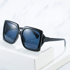 Lunettes de soleil carrées noires avec verres bleus sur un socle géométrique en marbre